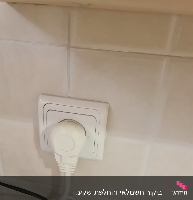 תקע חשמלי לבן בשקע על קיר אריחים